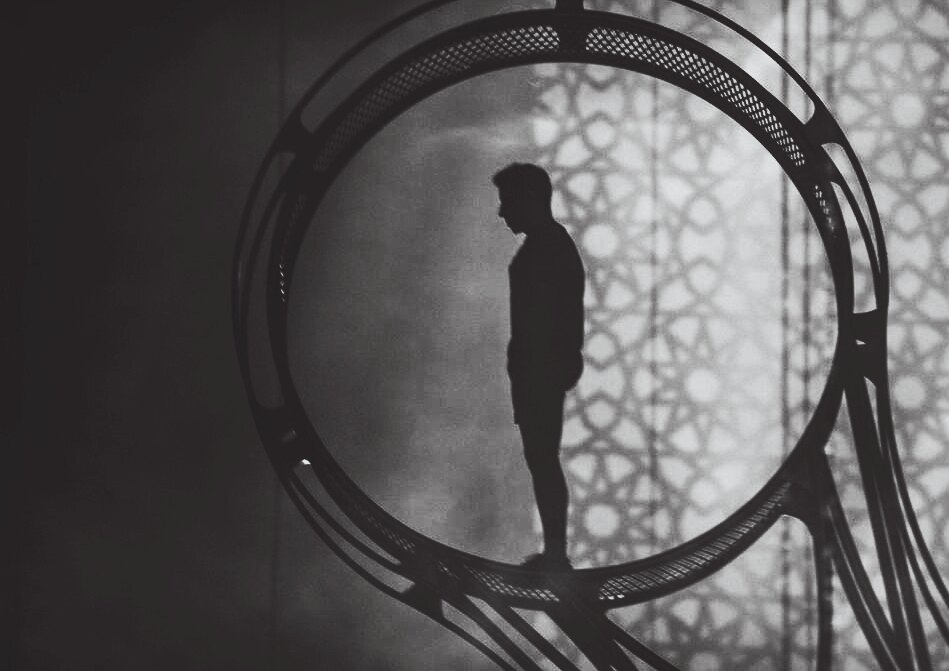 Performer silhouetted inside a circular stage structure